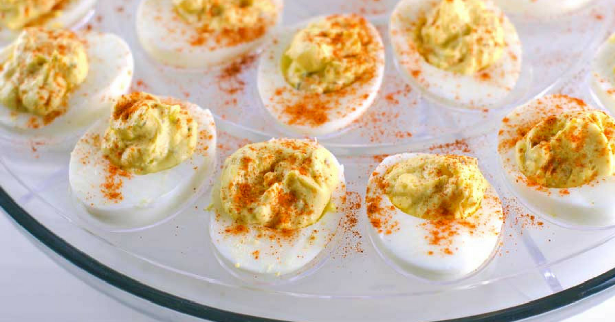 Southern deviled eggs dusted with paprika on a glass deviled eggs platter.