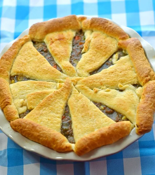 Whole baked beef pot pie sitting on the blue and white checkered background.