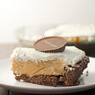 A slice of peanut butter pie with brownie crust garnished with a peanut butter cup.