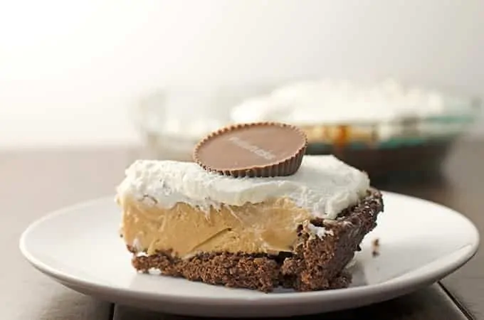 A slice of peanut butter pie with brownie crust garnished with a peanut butter cup.