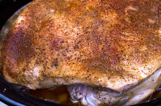 Seasoned pork shoulder sitting in the slow cooker ready to be cooked.