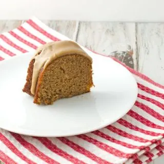 A slice of spiced bundt cake with caramel glaze on a white round dessert plate.