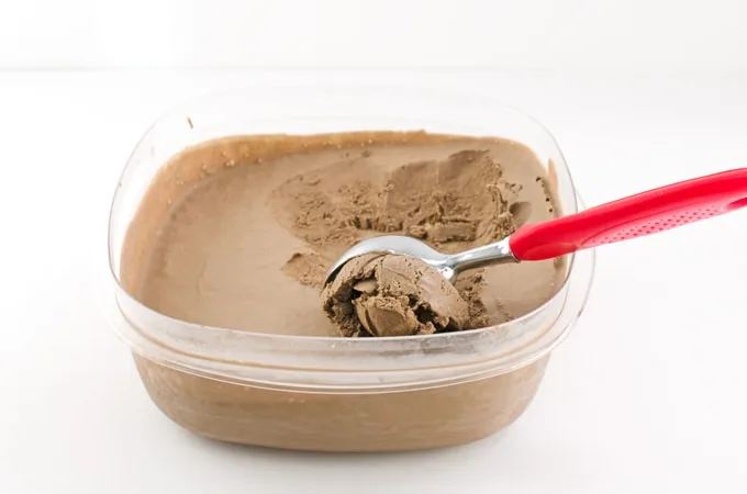  A container of homemade mocha ice cream with the scoop in the container
