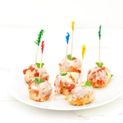 Prepared chicken parmesan meatballs on a white plate with toothpicks for easy appetizer eating