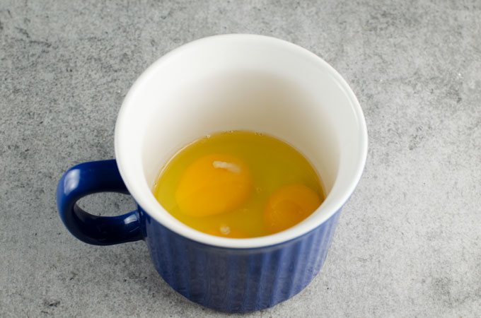 eggs in a mug getting ready to microwave