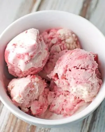 a white bowl filled with scoops of strawberry swirl ice cream