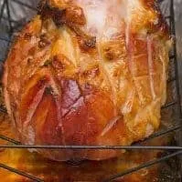 Glazed ham on a rack in a baking pan.