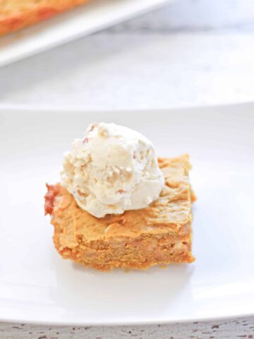 Pumpkin chocolate chip blondie an a plate with a scoop of butter pecan ice cream.