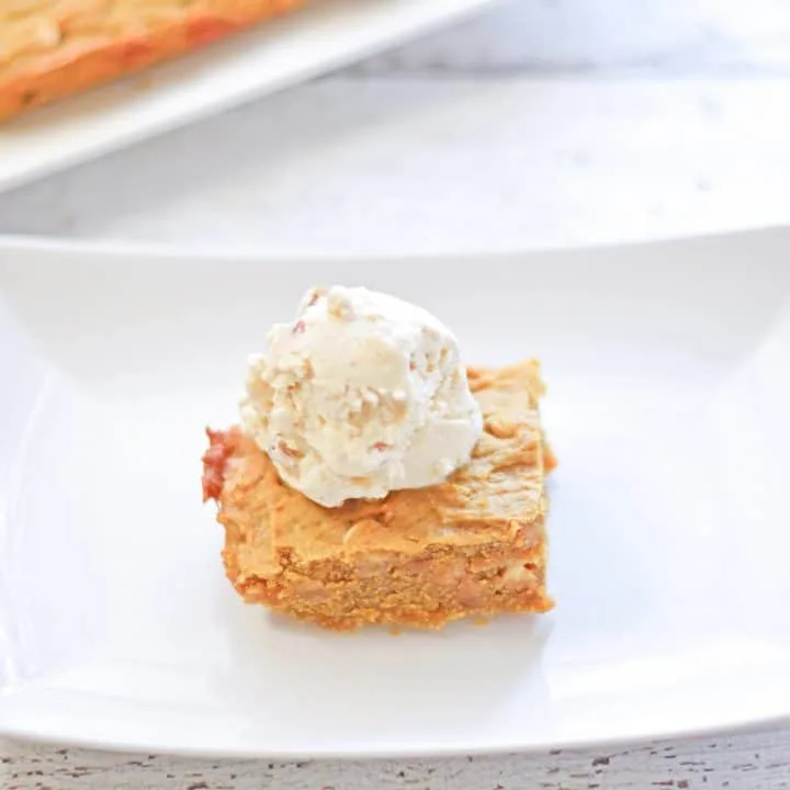 Pumpkin chocolate chip blondie an a plate with a scoop of butter pecan ice cream.