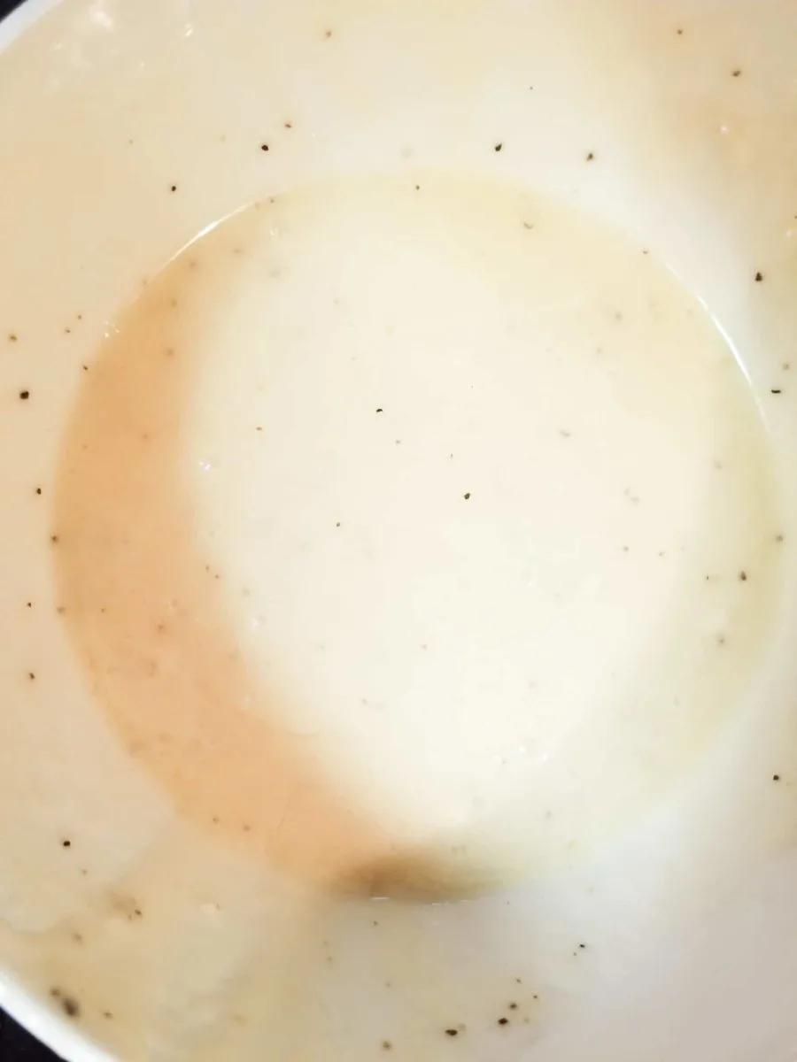 close up of broccoli salad dressing in a white bowl