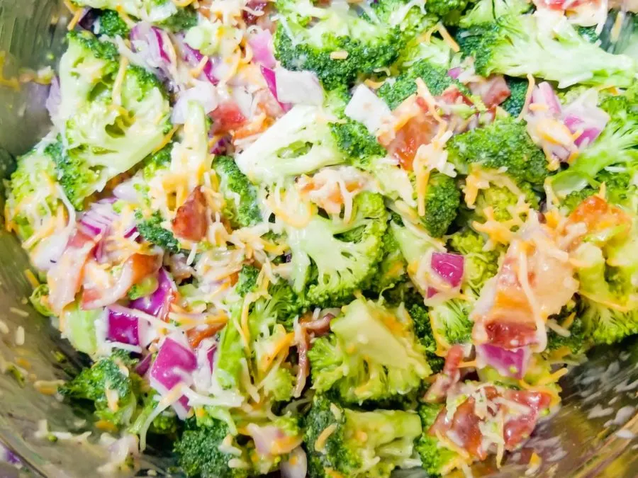 close up of dressed broccoli salad in a stainless steel bowl