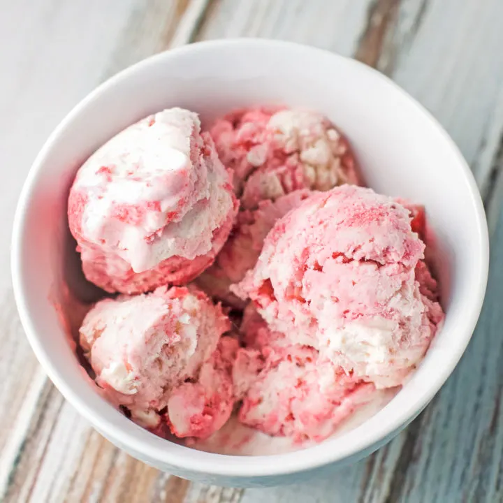A white bowl piled with scoops of strawberry swirl ice cream