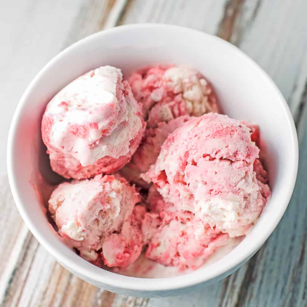 A white bowl piled with scoops of strawberry swirl ice cream