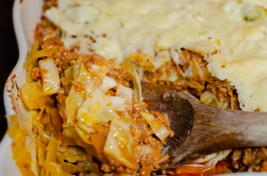 Creamy Unstuffed Cabbage Roll Casserole Recipe in casserole with a wooden spoonful being held to serve