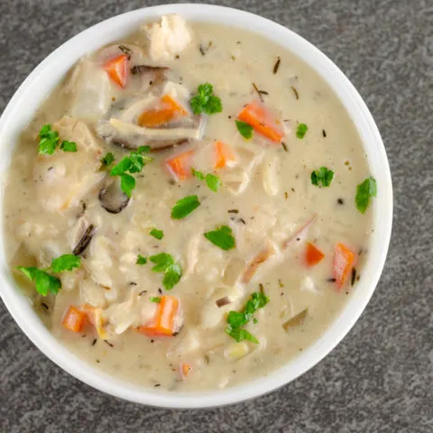 prepared creamy turkey wild rice soup with chopped parsley garnish in a white round bowl