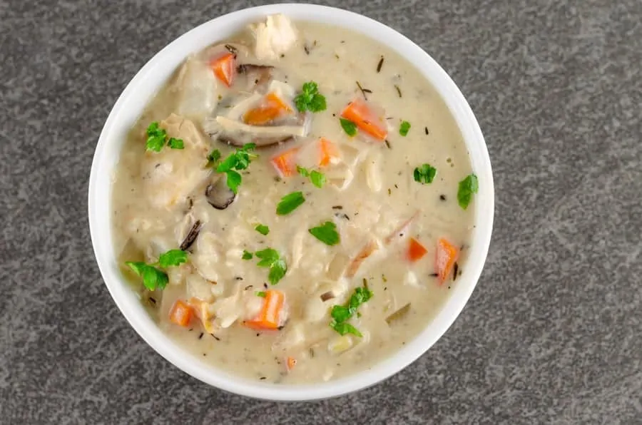 prepared creamy turkey wild rice soup with chopped parsley garnish in a white round bowl