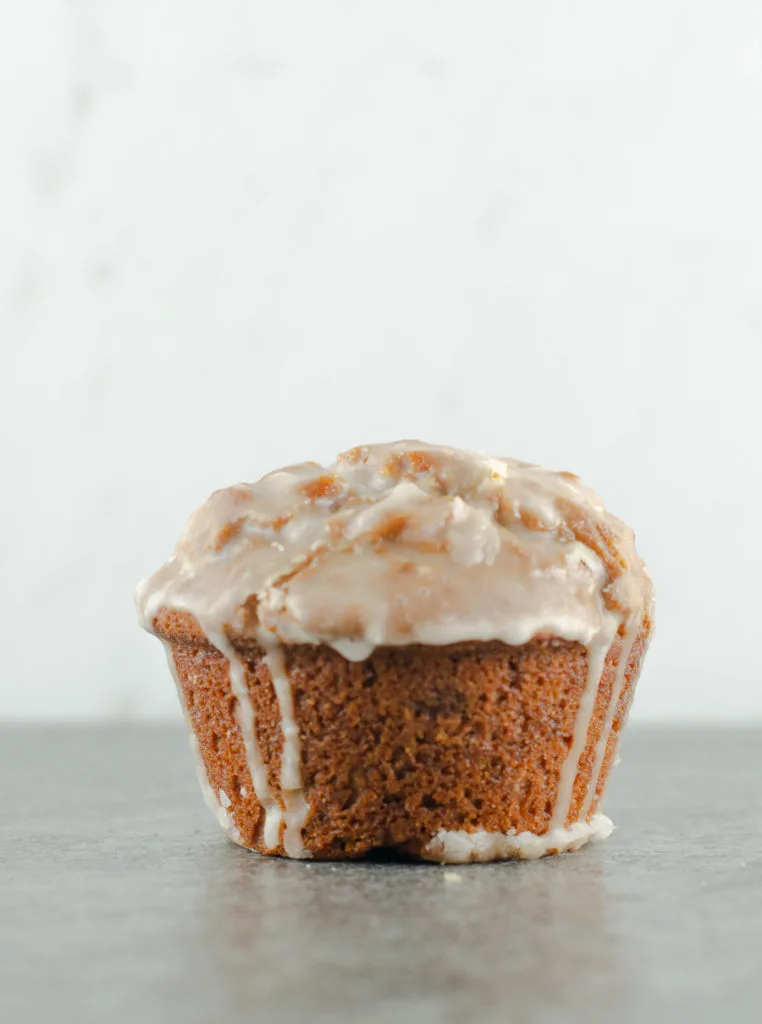 Frontal closeup of a glazed gingerbread muffin on a slate surface with marble background