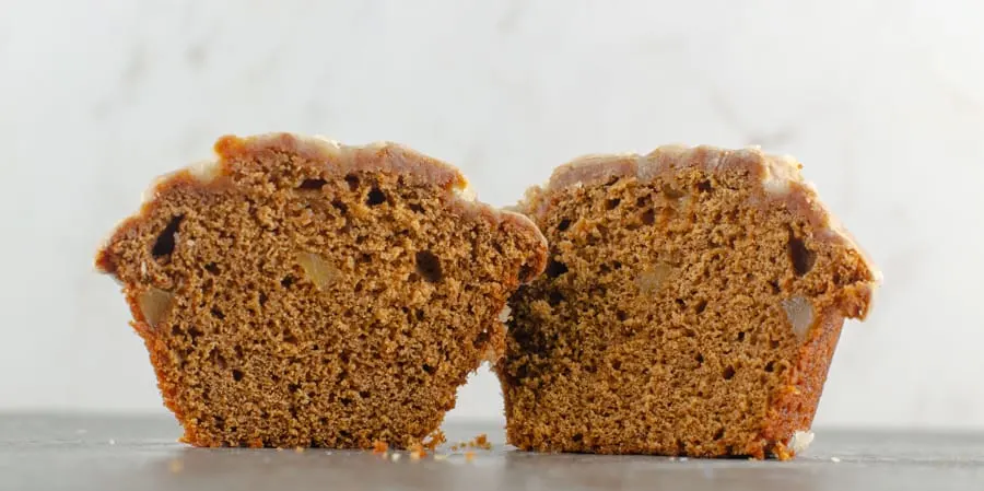 baked and glazed gingerbread muffin cut in half to see the inside with chunks of candied ginger