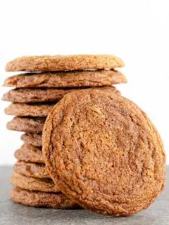 A stack of 10 baked ginger cookies with one leaning against the stack.