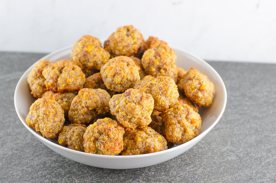 Baked Sausage Balls piled into a bwhite bowl on a black slate surface with marble background