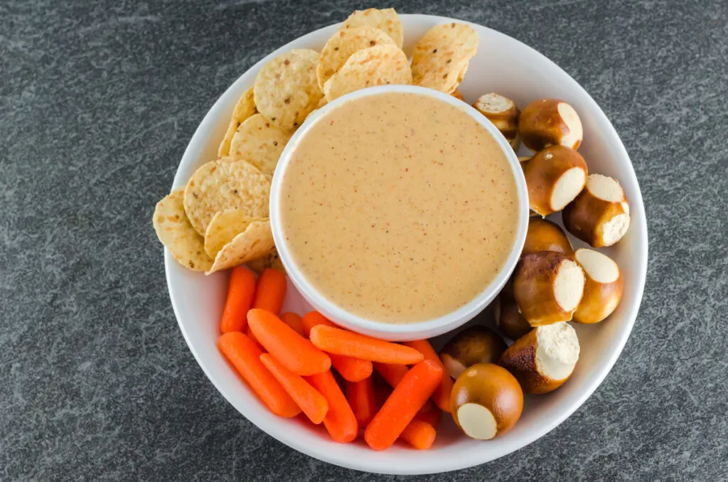 Overhead shot of queso dip ready to eat in a round white bowl with dippers.