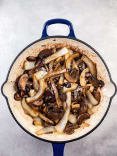 sauteed mushrooms and onions in a blue and white cast iron skillet