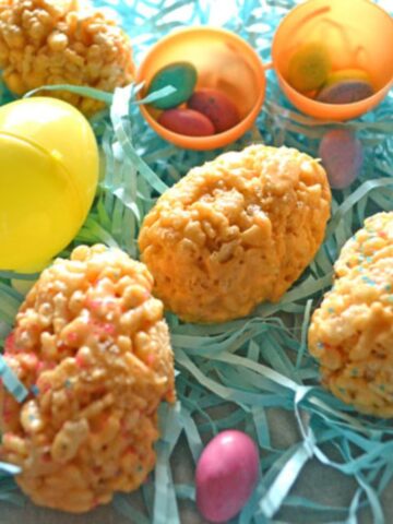 easter eggs made from butterscotch rice krispies on a bed of Easter paper grass, robins egg candies, and plastic easter eggs