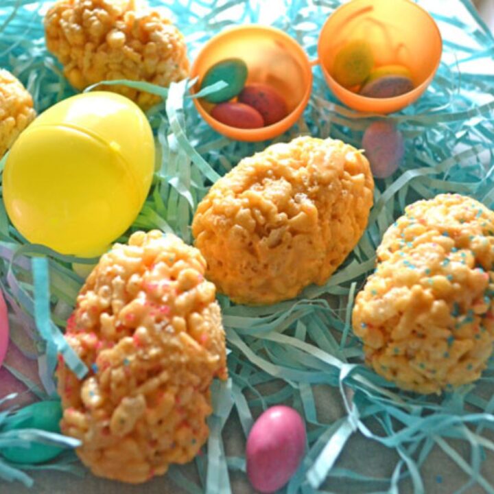 easter eggs made from butterscotch rice krispies on a bed of Easter paper grass, robins egg candies, and plastic easter eggs