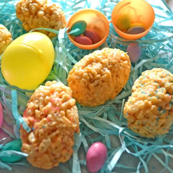 easter eggs made from butterscotch rice krispies on a bed of Easter paper grass, robins egg candies, and plastic easter eggs