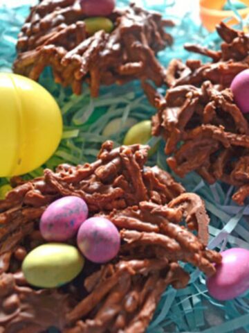 Easter egg nests treats made with chocolate covered chow mein noodles and robins egg candies to look like a bird's nest on easter paper grass