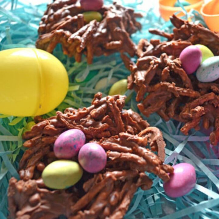 Easter egg nests treats made with chocolate covered chow mein noodles and robins egg candies to look like a bird's nest on easter paper grass