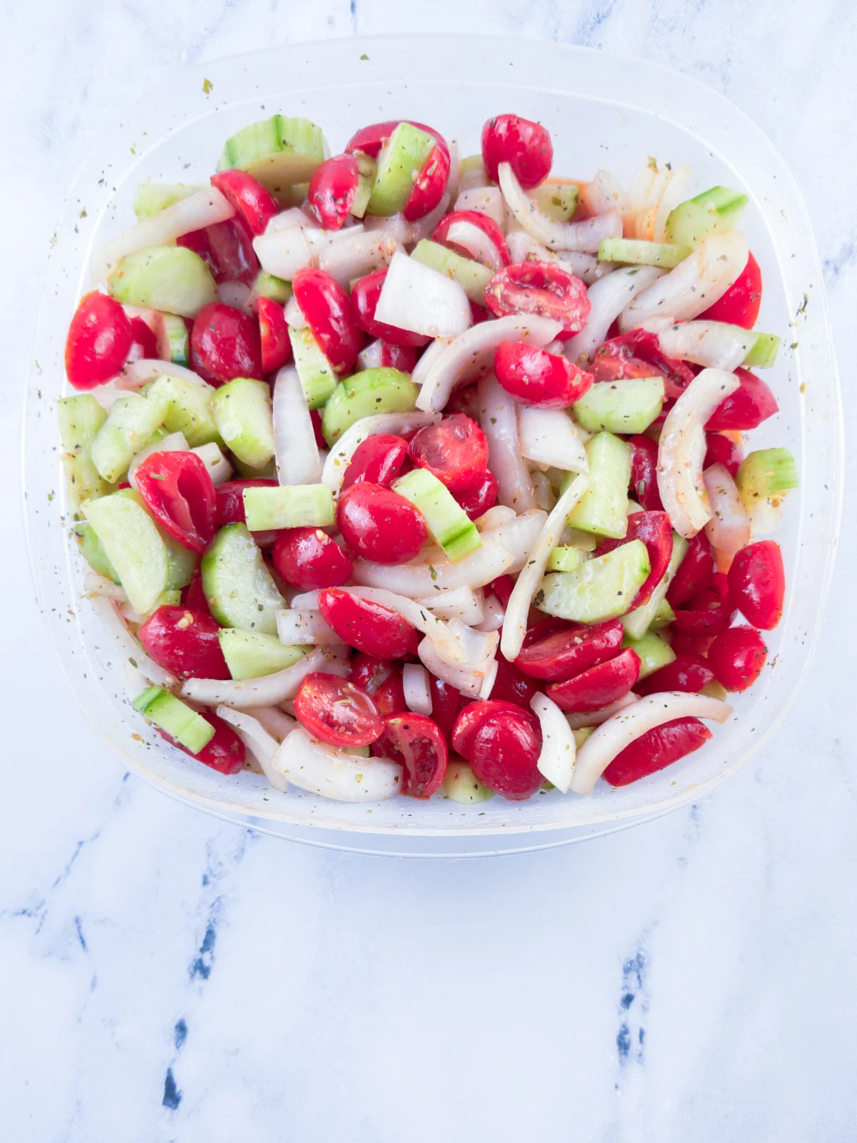 Marinated cucumber, tomato, and onion salad in a refrigerator safe container