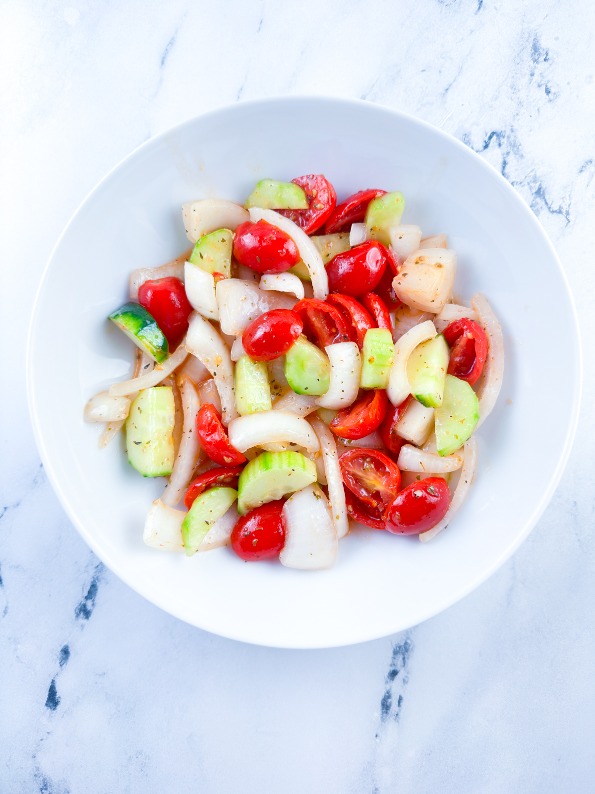 Marinated cucumber tomato and onion salad recipe ready to eat in a white bowl
