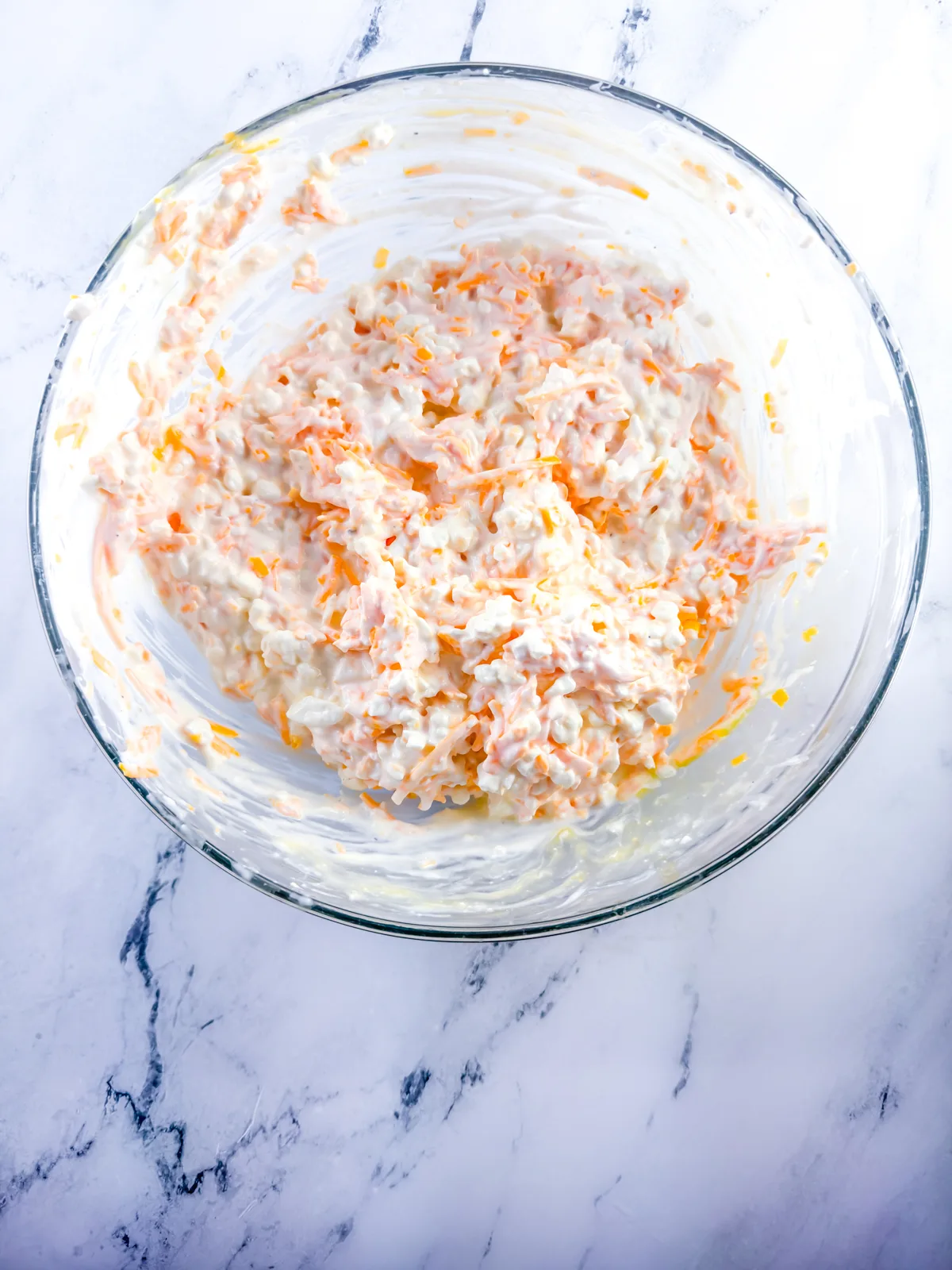 Cheese, egg, salt, pepper, and ground mustard mixed together in a large glass bowl.