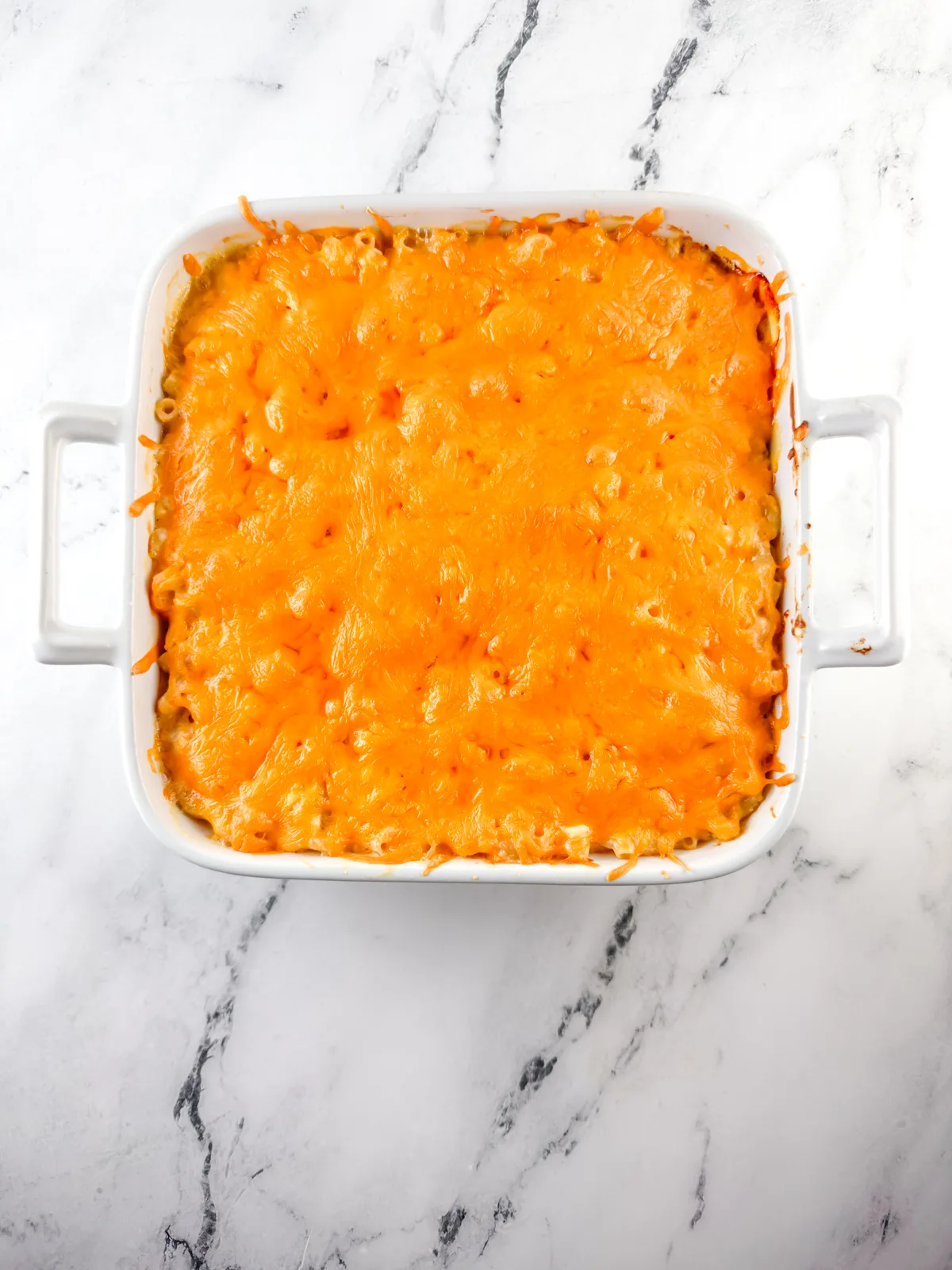 Baked macaroni and cheese in a white square baking dish.