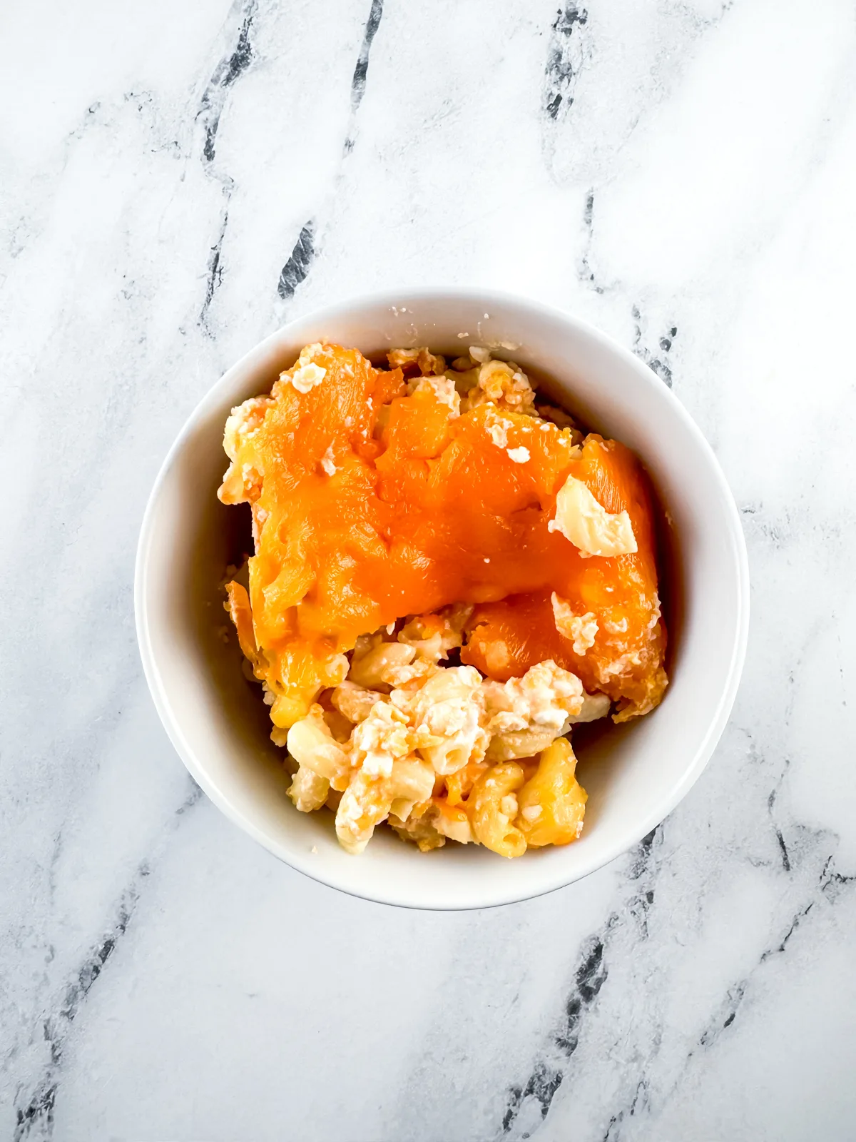 Baked macaroni and cheese in a white round bowl ready to eat.