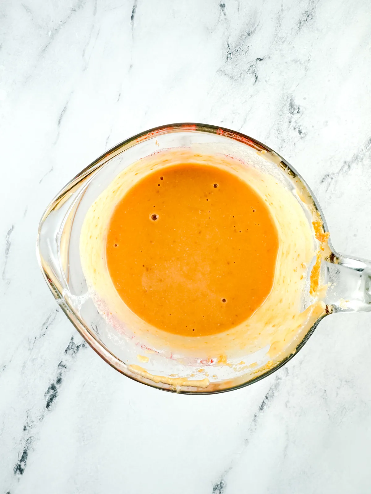 Canned pumpkin mixed with milk, butter, brown sugar, and salt in a glass measuring cup.