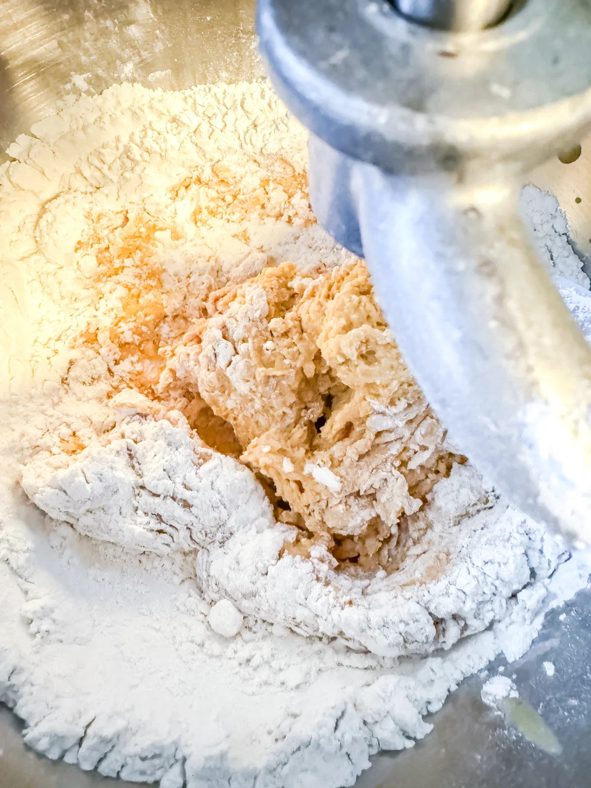 Mixing together flour, yeast, pumpkin mixture in a stand mixer.